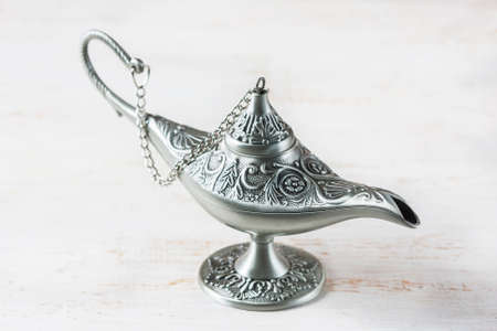 Silver aladdin's lamp on a white wooden background. Ramadan concept. Selective focusの写真素材