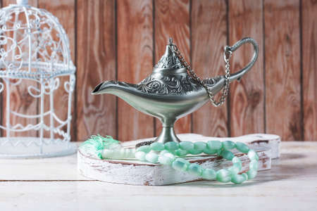 Green islamic prayer beads, dates and silver aladdin's lamp on wooden background. Ramadan concept. Selective focusの写真素材