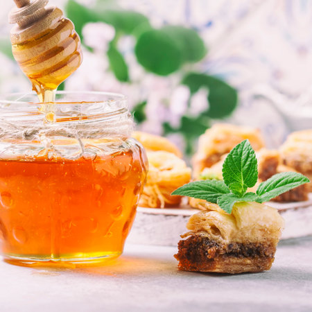 Honey, falling from a stick on a glass jar and ?raditional arabic dessert. Selective focusの写真素材