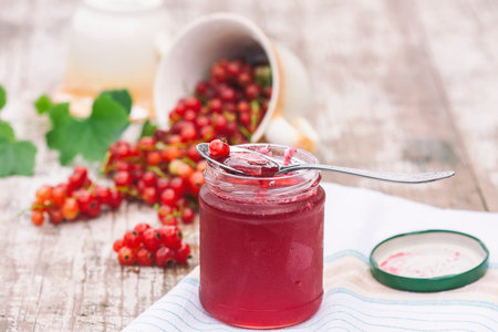 Red currants and jar of jam in garden. Natural light. Selective focus