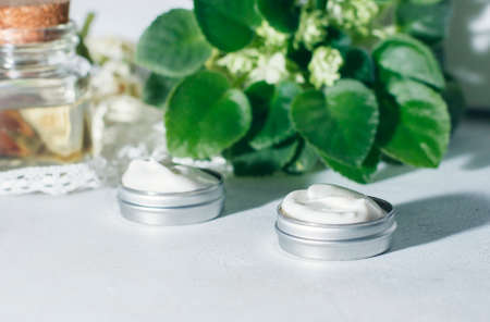 cosmetic cream with flowers on a light stone background.の写真素材
