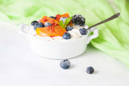 Healthy food, snacks or breakfast. Homemade Greek yogurt with blueberries, blackberries, persimmons and mint. On a concrete stone table. Selective focusの写真素材