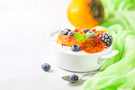 Healthy food, snacks or breakfast. Homemade Greek yogurt with blueberries, blackberries, persimmons and mint. On a concrete stone table.の写真素材