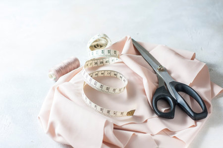 Everything for sewing. Beige fabric, sewing accessories and scissors. Seletive focus