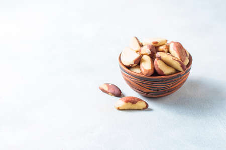 Wooden bowl with Brazil nuts on a light background. Healthy food.の写真素材