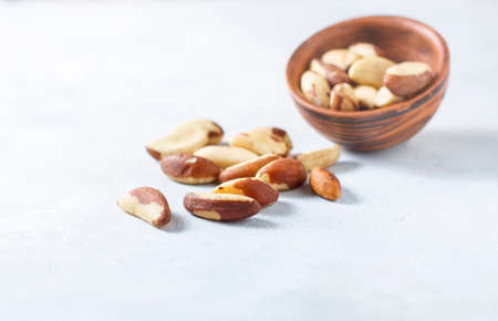 Wooden bowl with Brazil nuts on a light background. Healthy food.の写真素材