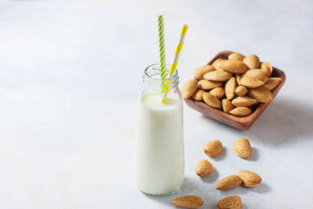 AHomemade almond milk and Raw almond in the sinks in a wooden bowl on a white background, selective focus. The concept of healthy food. Copy spaceの写真素材