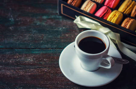 Beautiful breakfast. Morning cup of coffee with colorful macarons, on with flowers on dark background with copy space.の写真素材