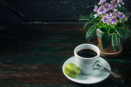 Beautiful breakfast. Morning cup of coffee with colorful macarons, on with flowers on dark background with copy space.の写真素材
