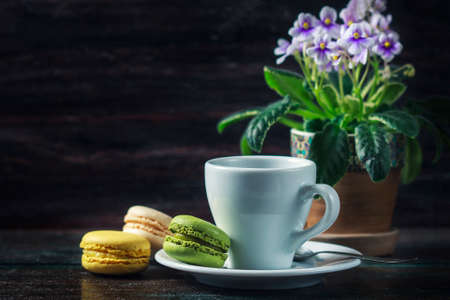 Beautiful breakfast. Morning cup of coffee with colorful macarons, on with flowers on dark background with copy space.の写真素材