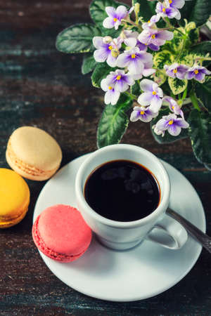 Beautiful breakfast. Morning cup of coffee with colorful macarons, on with flowers on dark background with copy space.の写真素材