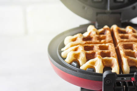 The process of making homemade waffles. Freshly baked waffles in a waffle iron. Selective focusの写真素材