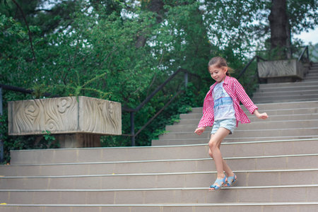 A girl with a card in her hands in a large park. Girl walks,looking for a way on map.