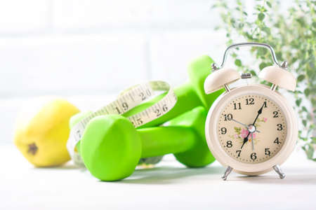 Alarm clock, apple, measuring tape and dumbbells, concept of diet. Selective focusの写真素材