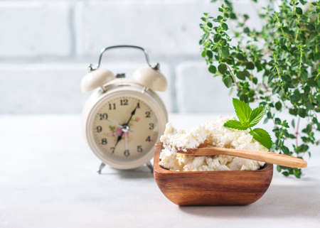Cottage cheese, alarm clock, diet concept. Selective focusの写真素材