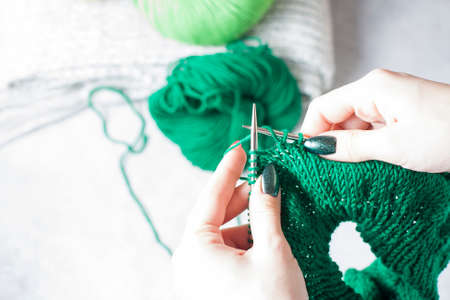 The girl knits knitting by the window. Hands of a young girl close up.の写真素材