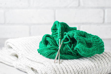 Green knitting yarn and knitting needles close-up.