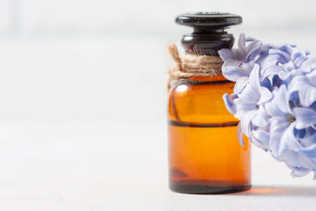 Bottle with essential oil and with lilac flowers on a white background. Macro. Selective focusの写真素材