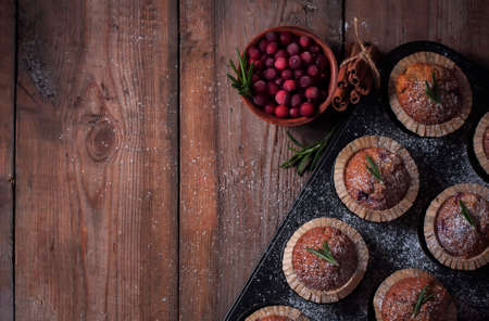 Fresh homemade Cranberry muffins in baking form on wooden table with Christmas decoration. Muffins in eco-friendly recyclable paper packaging.の写真素材