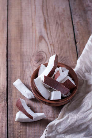 Ceramic bowl with coconut slices on a wooden background. Selective focus, copy space.の写真素材