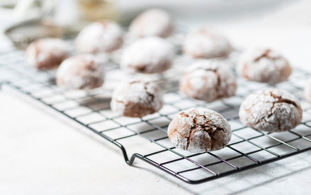 Cracked chocolate chip cookies in icing sugar. Chocolate christmas cookies on a white wooden table....