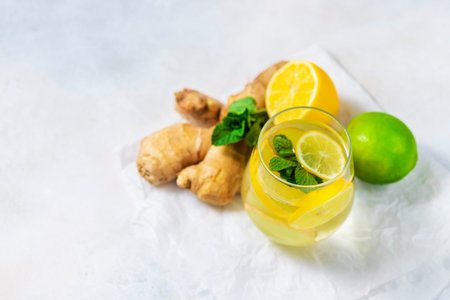 Ginger-lemon drink. Homemade Organic ginger in a glass with Lemon and mint on white table. Trendy...