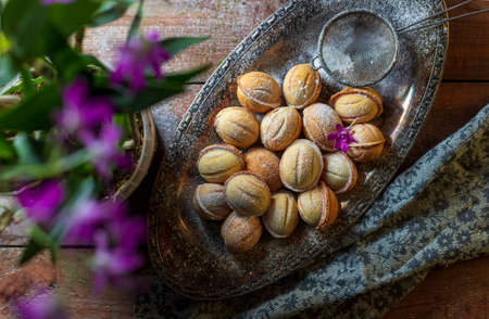 Homemade cookies in the form of nuts filled with sweet condensed milk on an old wooden background. Homemade Russian cookies. Selective focus, top view, copy space.の写真素材