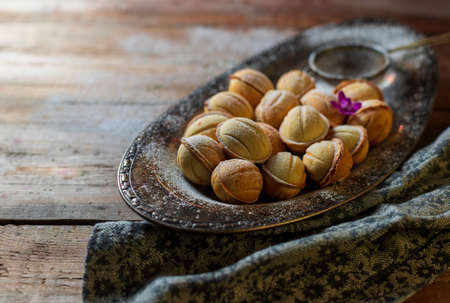 Homemade cookies in the form of nuts filled with sweet condensed milk on an old wooden background. Homemade Russian cookies. Selective focus, top view, copy space.の写真素材