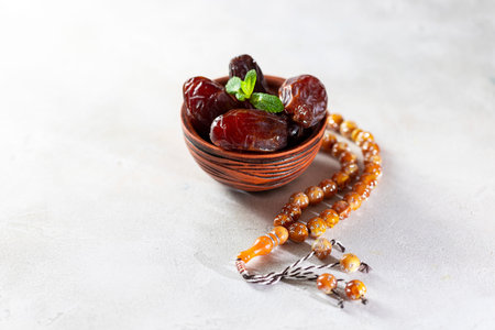 Plate with dates, decorative arabic lantern and rosary on a light background. Holy month of Ramadan...