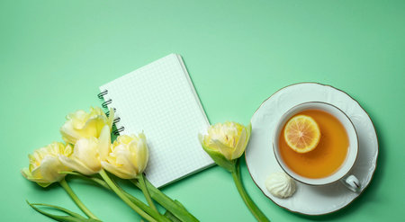 Bouquet of yellow tulips and a cup of tea with lemon close-up. Composition for Valentine's Day,...
