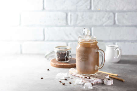 Ice coffee with milk and ice in a glass jar on a light background. Bamboo drinking straws with Zero - waste. Glass mason jar. Selective focus, copy spaceの写真素材