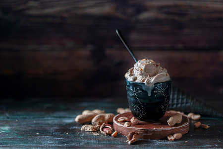 Ice cream with peanuts on a dark background. Summer dessert with nuts. Selective focus, copy space for text.の写真素材