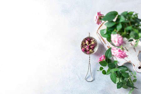 Buds of tea rose for tea in a vintage strainer on a light background. Selective focus, copy space. Top view.の写真素材
