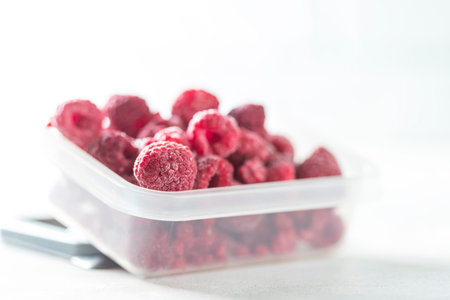 Frozen raspberry close up on a light background. Top view, copy space. Fresh organic berries macro....
