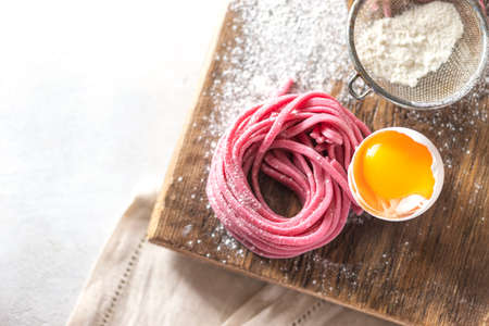 Fresh Hand made beetroot pasta on wooden cutting board. Raw purple spaghetti, fettuccine. Top view. Selective focus, copy space.の写真素材