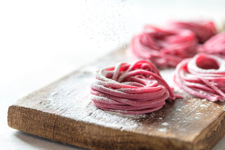 Fresh Hand made beetroot pasta on wooden cutting board. Raw purple spaghetti, fettuccine. Selective...