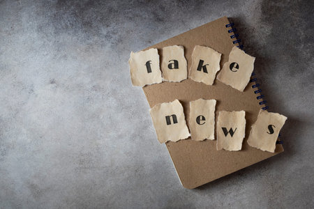 Fake news concept, letters written on old paper, on gray concrete background. Social media concept....
