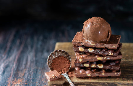 A ball of chocolate ice cream on a chocolate bar with nuts. Selective focus, copy space