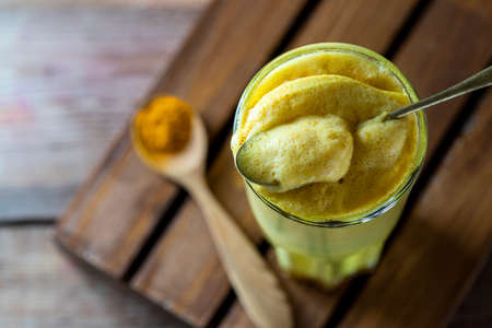 Golden milk, turmeric latte on wooden background. Natural detox beverage with spices. Selective focus, copy spaceの写真素材