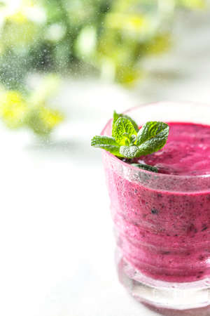 Vitamin smoothie from blackcurrant berries with yogurt and banana in a crystal glass. Healthy eating concept. Selective focus, copy spaceの写真素材