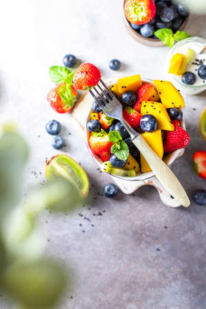 Fresh organic fruit salad on a light concrete background. Top view. Copy space.の写真素材