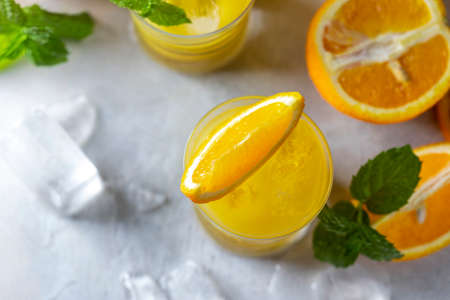 Fresh orange juice, orange slices, mint leaves and ice on a wooden table. Selective focus, copy spaceの写真素材