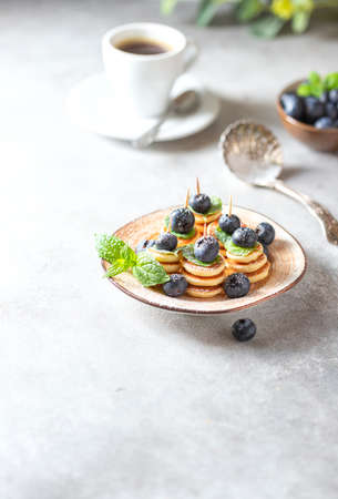Fashionable food - mini pancakes with blueberries and mint on a light concrete background. Copy space, selective focusの写真素材