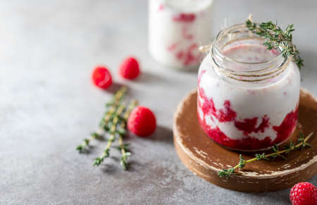 Raspberry smoothie, milkshake in a glass jar on a dark wooden background. Yogurt cocktail. Natural summer detox drink. Healthy eating concept.の写真素材
