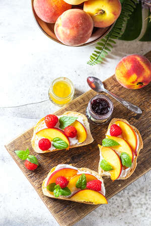 Summer snack - sandwiches with cream cheese and fresh peaches on a light concrete background. Homemade Summer Breakfast. Copy space, selective focus, flat layの写真素材