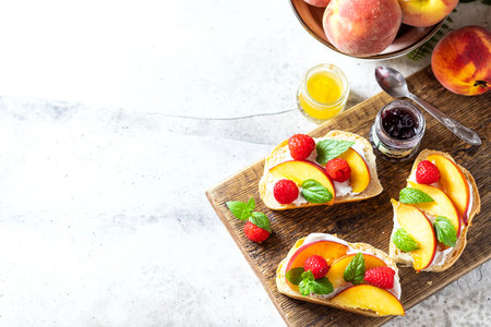 Summer snack - sandwiches with cream cheese and fresh peaches on a light concrete background....