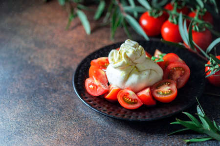 Traditional italian food barrata and tomatoes on a dark background. Selective focus, copy spaceの写真素材