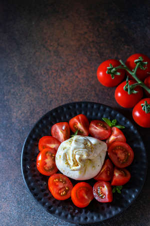 Traditional italian food barrata and tomatoes on a dark background. Selective focus, copy spaceの写真素材
