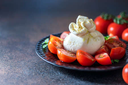 Traditional italian food barrata and tomatoes on a dark background. Selective focus, copy spaceの写真素材