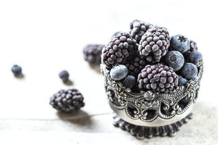 Fresh Frozen blackberry on a gray concrete background. Season concept, season. Healthy nutrition,...